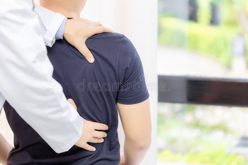 Doctor Examining Sore Back Muscles of Young Man Sitting Shirtless and Slumped Over on Table stock image Doctor Examining Sore Back Muscles of Young Man Sitting Shirtless and Slumped Over on Table stock image