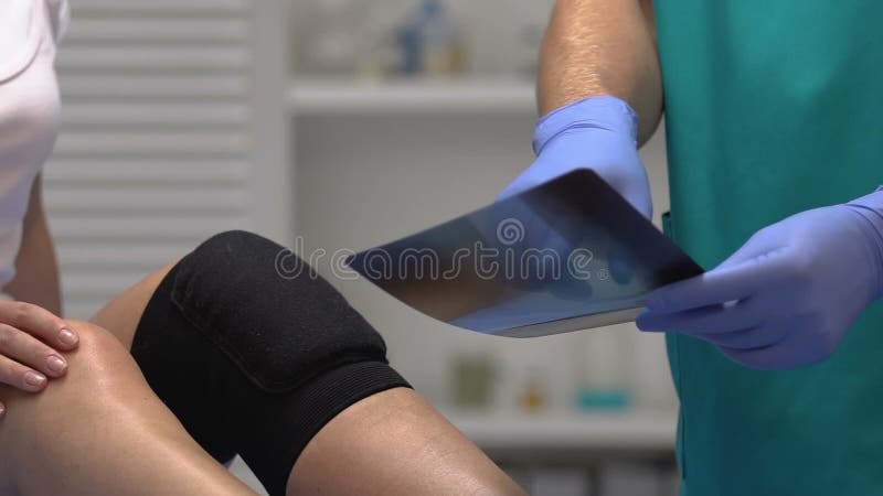 Doctor explaining x-ray results to patient with compression knee brace, trauma