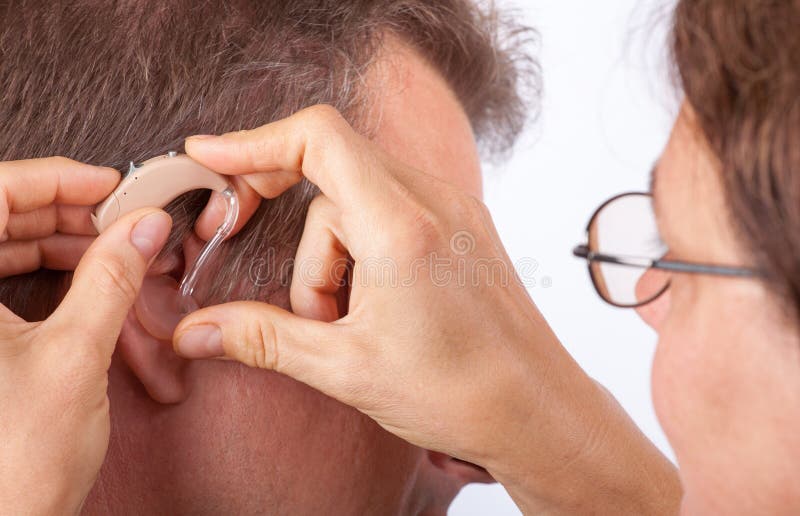 Doctor fitting senior man patient with hearing aid