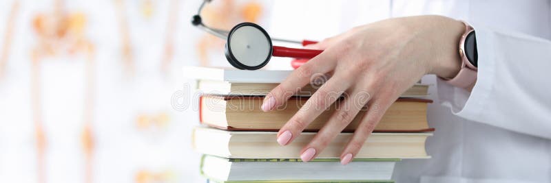Doctor hands are holding stack of books and stethoscope royalty free stock image