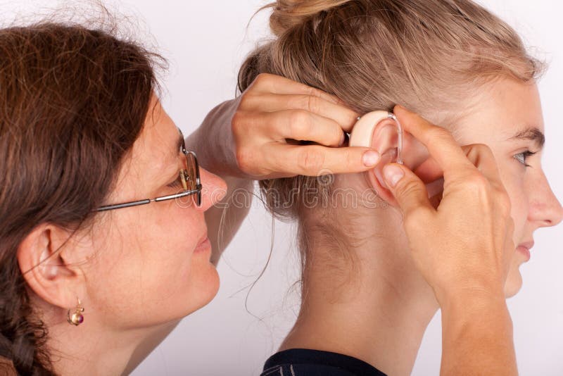 Doctor helps inserting a hearing aid