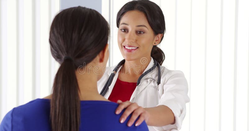 Doctor hispano escuchando hablar a paciente afroamericano almacen de metraje de vídeo