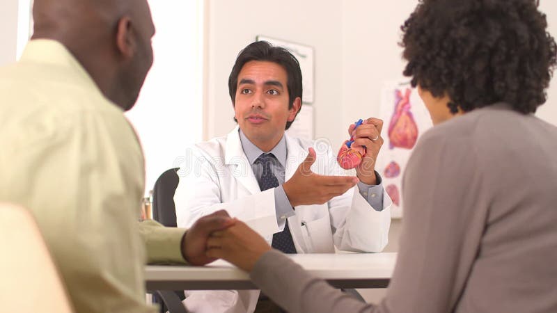 Doctor hispano hablando con pareja afroamericana sobre problemas cardíacos metrajes