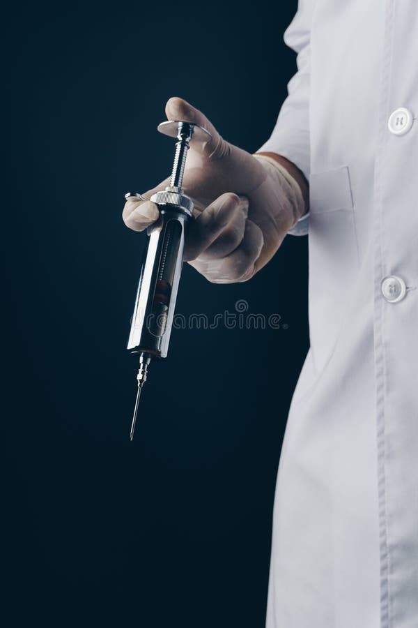 doctor-holding-big-stainless-steel-syringe-dark-background-124274601.jpg