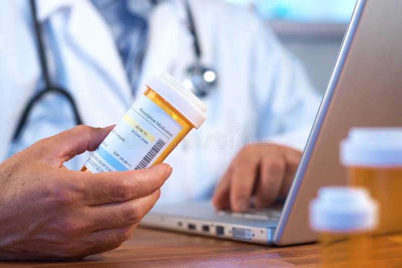 Doctor holding prescription bottle with laptop