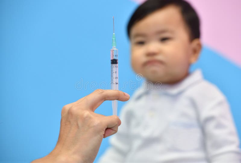 Doctor holding syringe with vaccine for Asian baby stock photo Doctor holding syringe with vaccine for Asian baby stock photo