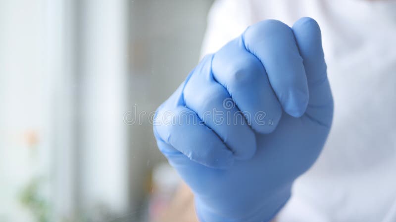 Doctor in a Hospital Room Knocking on a Transparent Door with Hand Wearing Gloves.
