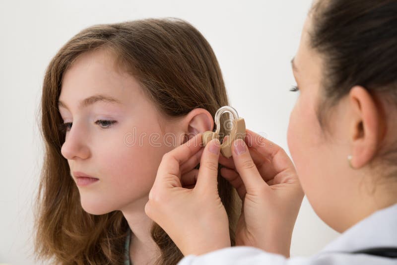 Doctor Inserting Hearing Aid In The Ear Of A Girl