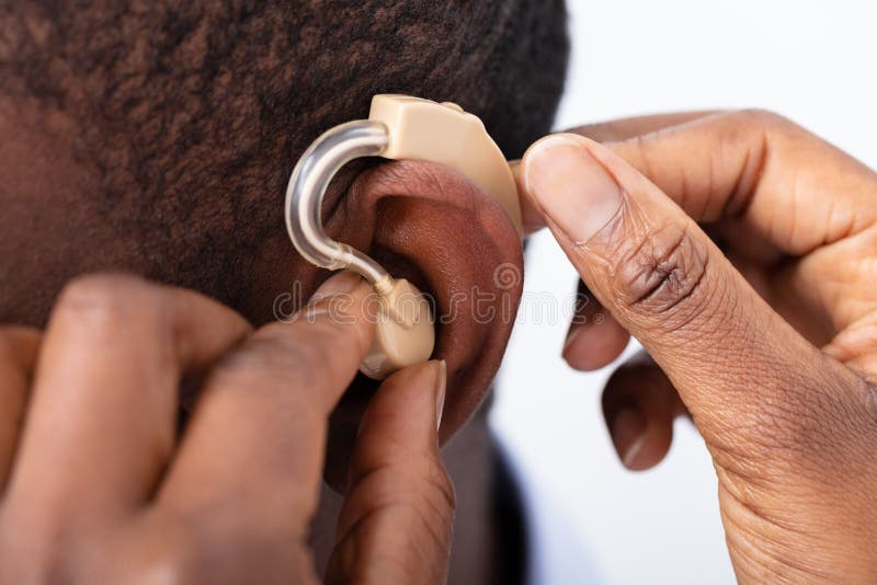 Doctor Inserting Hearing Aid In Patient`s Ear