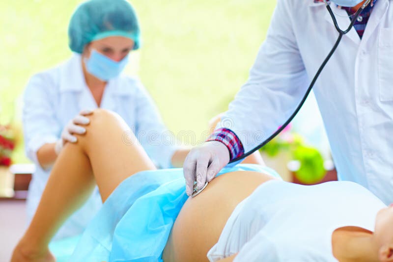 Doctor listens to the baby s heartbeat during childbirth