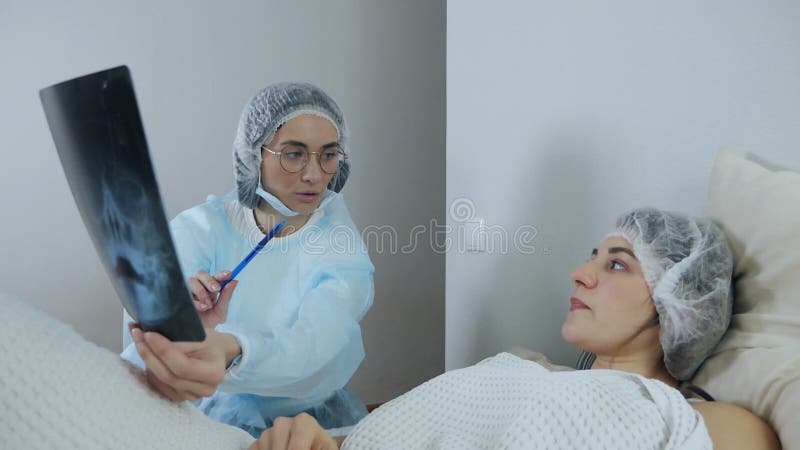 Doctor looking at and discussing the results of computed tomography of a patient lying on a bed in an emergency room