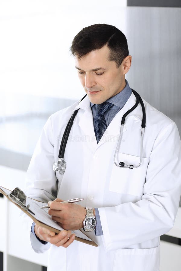 Doctor man using clipboard for filling up medication history records. Perfect medical service in clinic. Physician at stock image