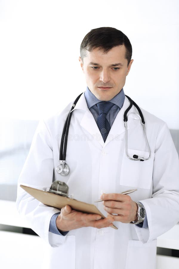 Doctor man using clipboard for filling up medication history records. Perfect medical service in clinic. Physician at royalty free stock photo
