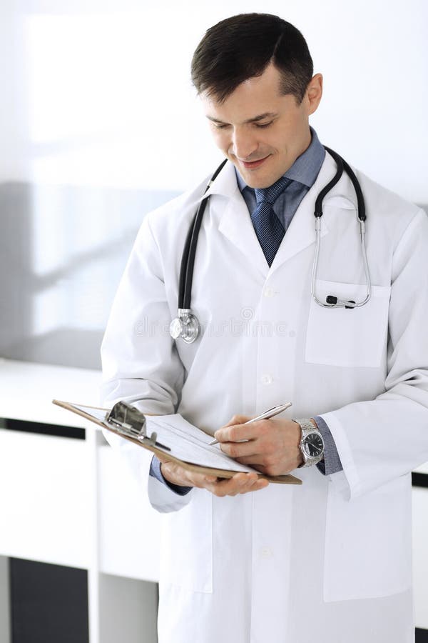 Doctor man using clipboard for filling up medication history records. Perfect medical service in clinic. Physician at royalty free stock photos