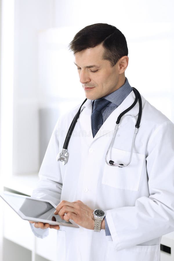 Doctor man using tablet computer for network research or virtual disease treatment. Perfect medical service in clinic royalty free stock photography