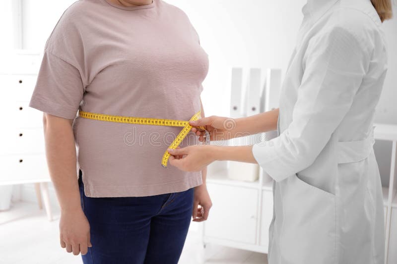 Doctor measuring waist of overweight woman in clinic