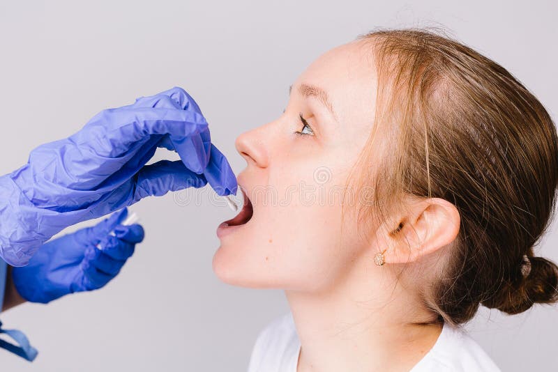 Doctor in medical steril gloves taking mouth fluid swab sample for covid 19 test. Getting Covid-19 Sample from Mouth