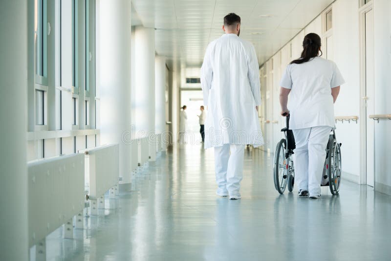 Doctor and nurse pushing wheelchair with patient in hospital