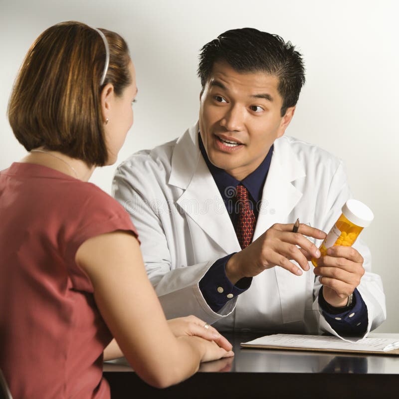 Asian American dottore maschio, spiegando farmaco per Caucasica paziente di sesso femminile.