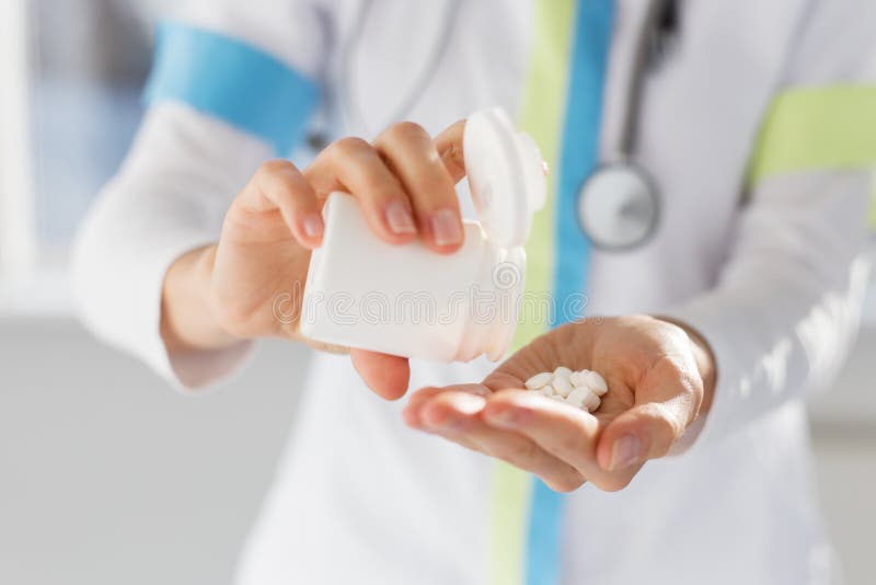 Doctor pouring white medicine pills in hand