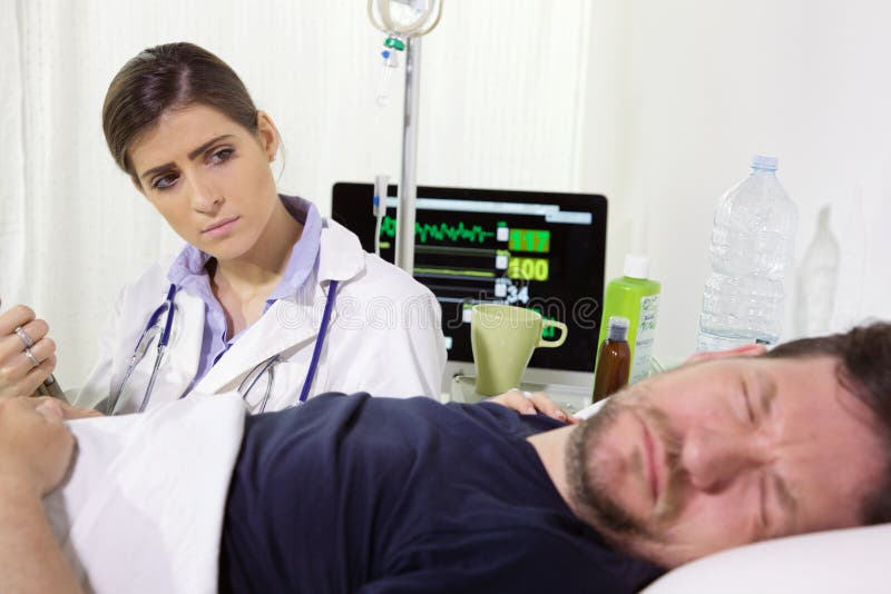 Doctor preocupante en hospital que comprueba dolor paciente de la sensación el dormir imagen de archivo libre de regalías Doctor preocupante en hospital que comprueba dolor paciente de la sensación el dormir imagen de archivo libre de regalías
