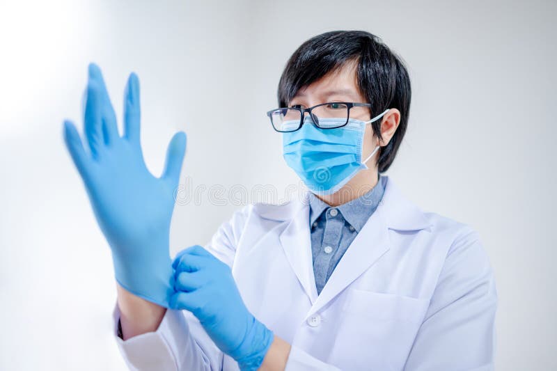 Doctor putting disposable latex gloves on hand