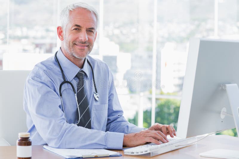 Doctor que mecanografía y que usa su ordenador imagen de archivo libre de regalías Doctor que mecanografía y que usa su ordenador imagen de archivo libre de regalías