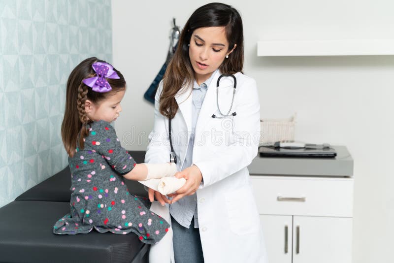Doctor que pone vendaje en la mano herida de la niña fotografía de archivo