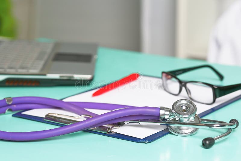 Doctor`s workspace working table with patient`s discharge blank paper form, medical prescription, stethoscope on desk