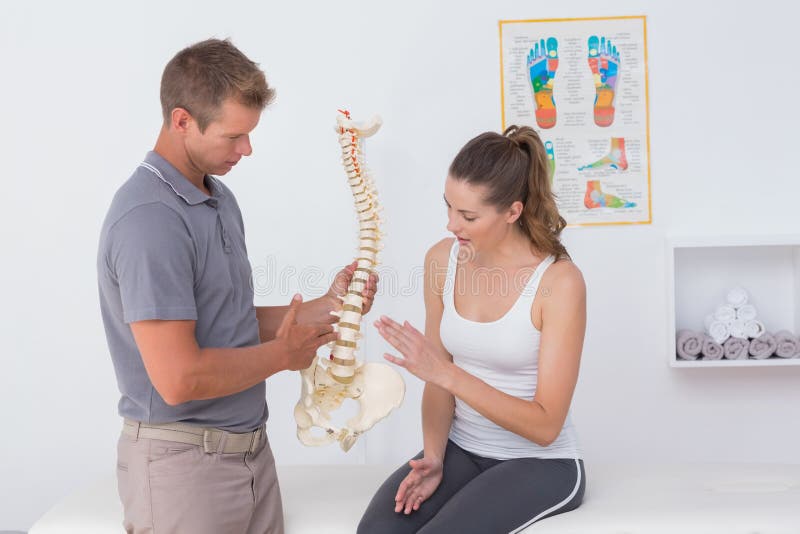 Doctor showing anatomical spine to his patient in medical office