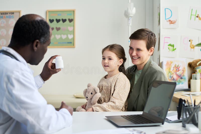 Doctor Showing Medication to Mother and Daughter in Office royalty free stock image