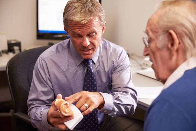 Doctor Showing Senior Male Patient Model Of Human Ear