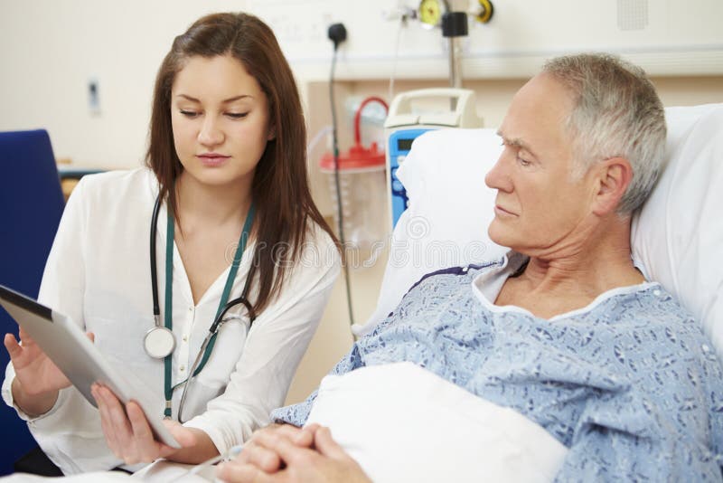 Doctor Sitting by Male Patient S Bed Using Digital Tablet Stock Photo