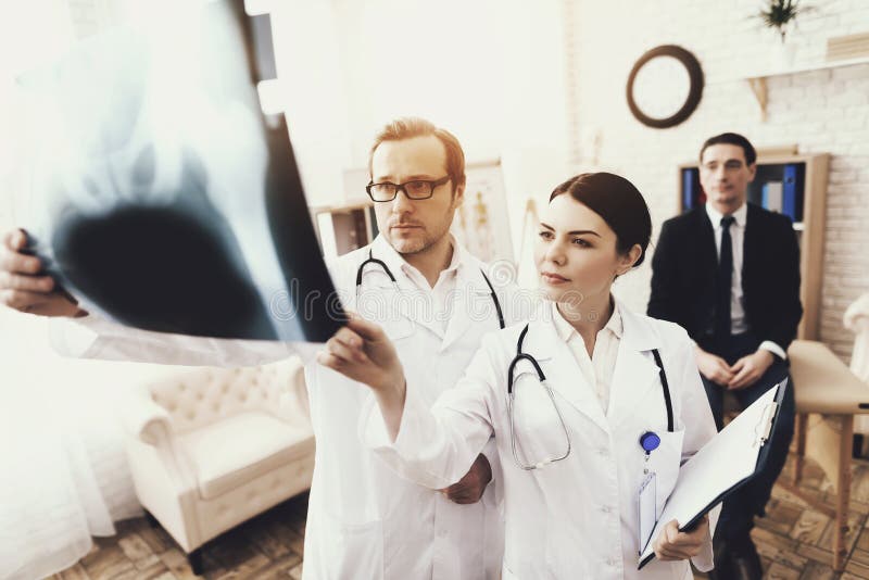 Doctor with stethoscope and nurse examines X-ray of businessman, of patient. royalty free stock photo Doctor with stethoscope and nurse examines X-ray of businessman, of patient. royalty free stock photo