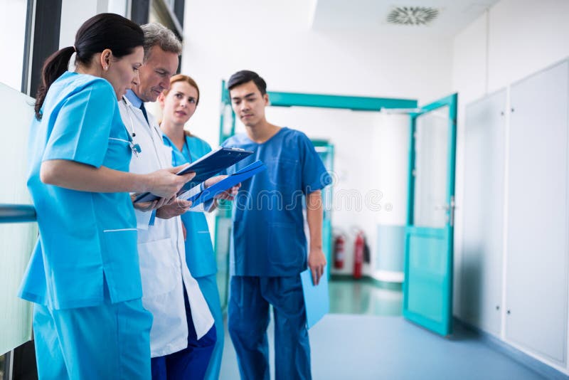 Doctor and surgeons discussing with report in corridor stock images