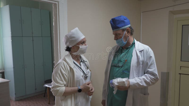 Doctor talking with a nurse standing in a hospital hall. Mature male doctor talking to a young female nurse. City stock images Doctor talking with a nurse standing in a hospital hall. Mature male doctor talking to a young female nurse. City stock images