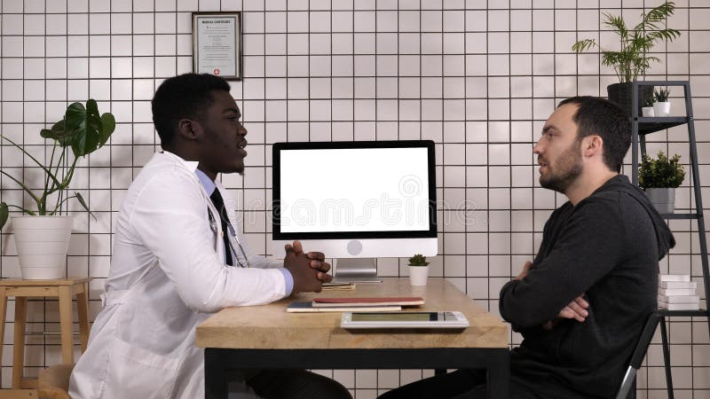 View to the screen of computer.Doctor talking to his male patient. White Display. Professional shot in 4K resolution. 017. You can use it e.g. in your commercial video, medical, business, presentation, broadcast