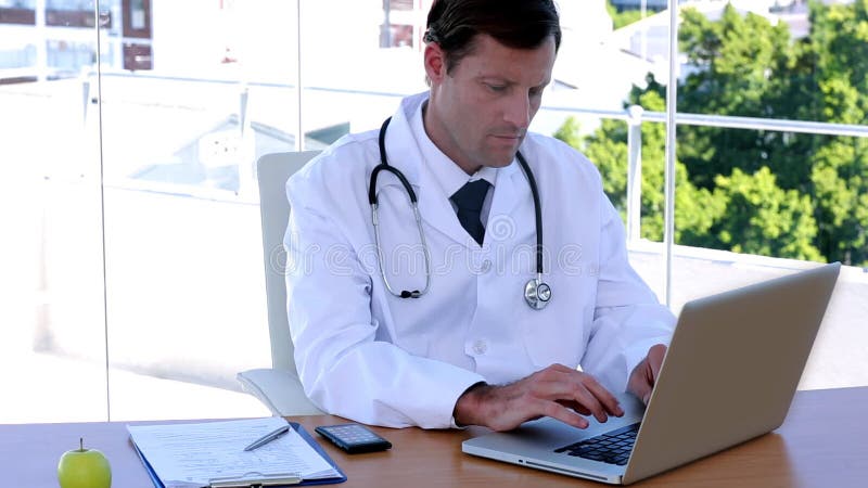 Doctor typing at his desk stock video footage