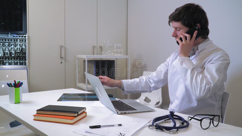 Doctor using smartphone has phone conversation.