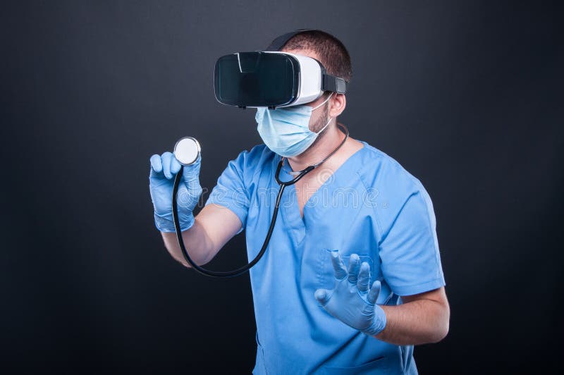 Doctor wearing scrubs using virtual reality glasses and stethoscope stock image