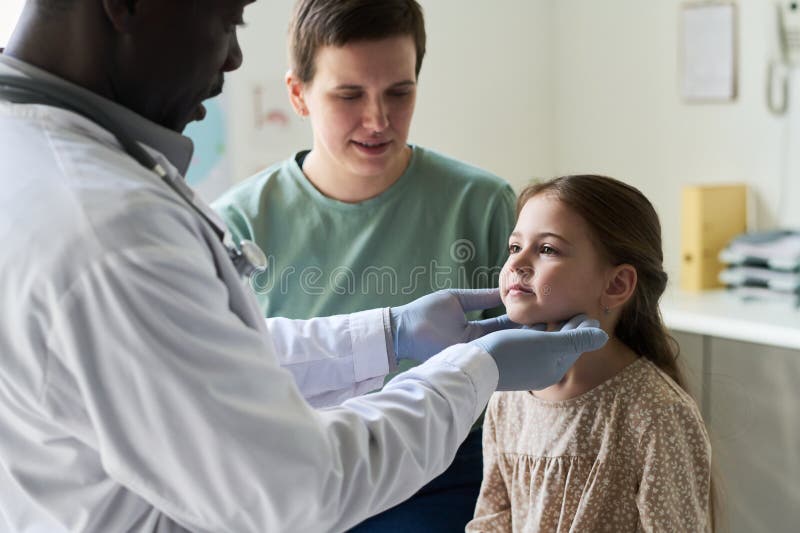 Doctor Examining Young Girl Accompanied by Mother in Clinic stock photography