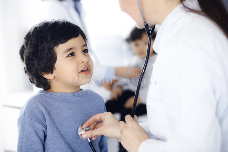 Doctor-woman examining a child patient by stethoscope. Cute arab boy and his brother at physician appointment. Medicine. Concept