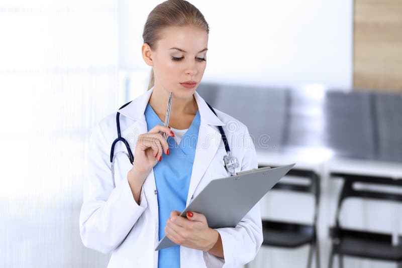 Doctor woman filling up medication history record while standing in emergency hospital office. Physician at work, studio. Portrait. Medicine and health care royalty free stock images Doctor woman filling up medication history record while standing in emergency hospital office. Physician at work, studio. Portrait. Medicine and health care royalty free stock images