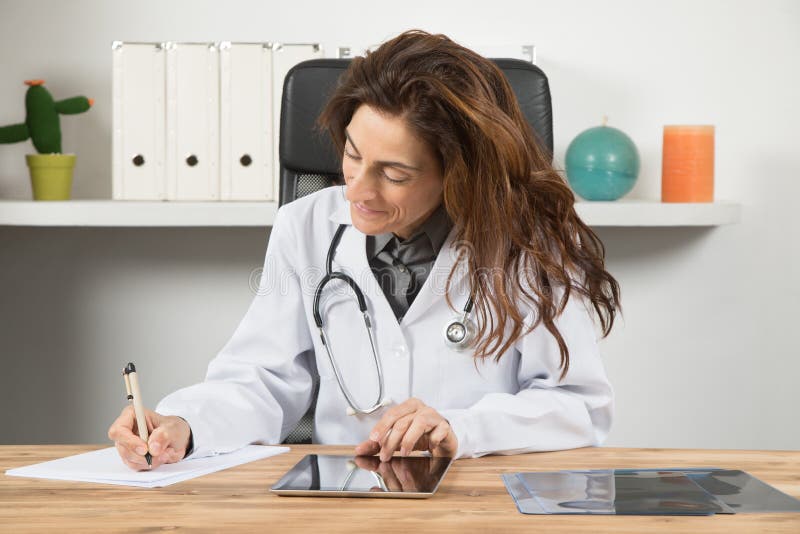 Doctor woman writing on paper with digital tablet in desktop