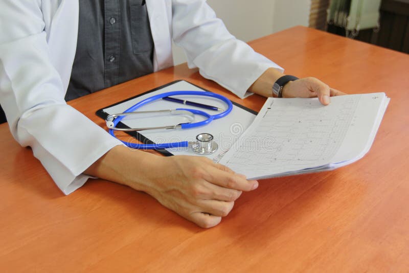 Doctor working in hospital and checking the results electrocardiogram and stethoscope on paper in clipboard, medical care and stock images Doctor working in hospital and checking the results electrocardiogram and stethoscope on paper in clipboard, medical care and stock images