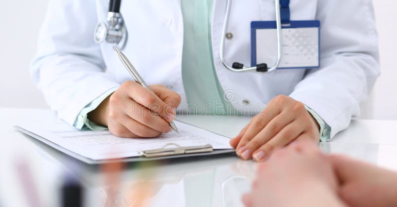 Doctor y el hablar paciente mientras que se sienta en el escritorio en la oficina del hospital, primer de manos humanas Medicina imagen de archivo libre de regalías Doctor y el hablar paciente mientras que se sienta en el escritorio en la oficina del hospital, primer de manos humanas Medicina imagen de archivo libre de regalías