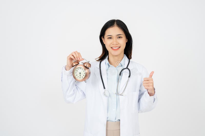 Doctora femenina sonriendo y aguantando el reloj. aislado en fondo blanco fotografía de archivo libre de regalías