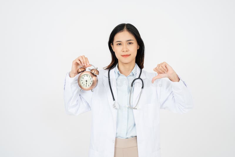 Doctora femenina sonriendo y aguantando el reloj. aislado en fondo blanco foto de archivo