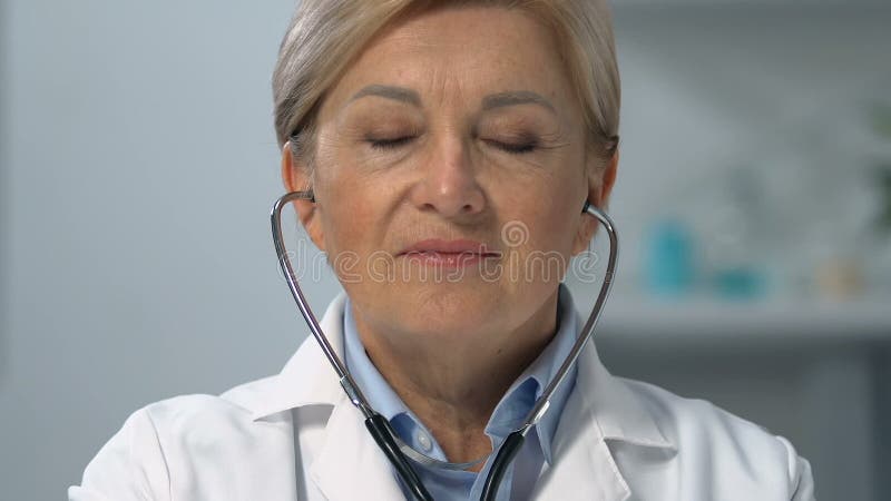 Doctoriță experimentată care se ocupă de stetoscop și care caută o programare stock video