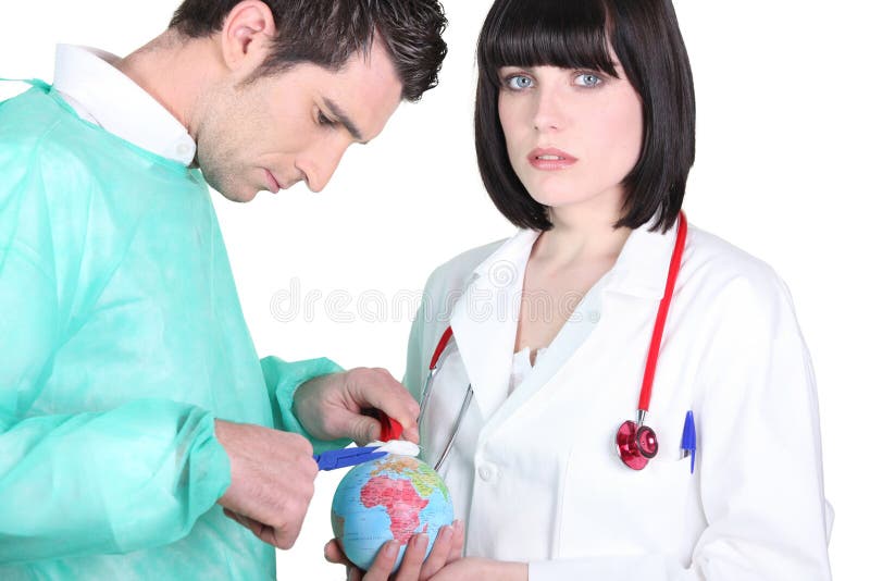 Doctors treating a mini globe royalty free stock photos